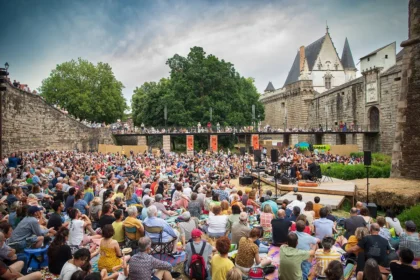 Public devant une scène éclairée pendant un concert à Nantes dans une grande salle.